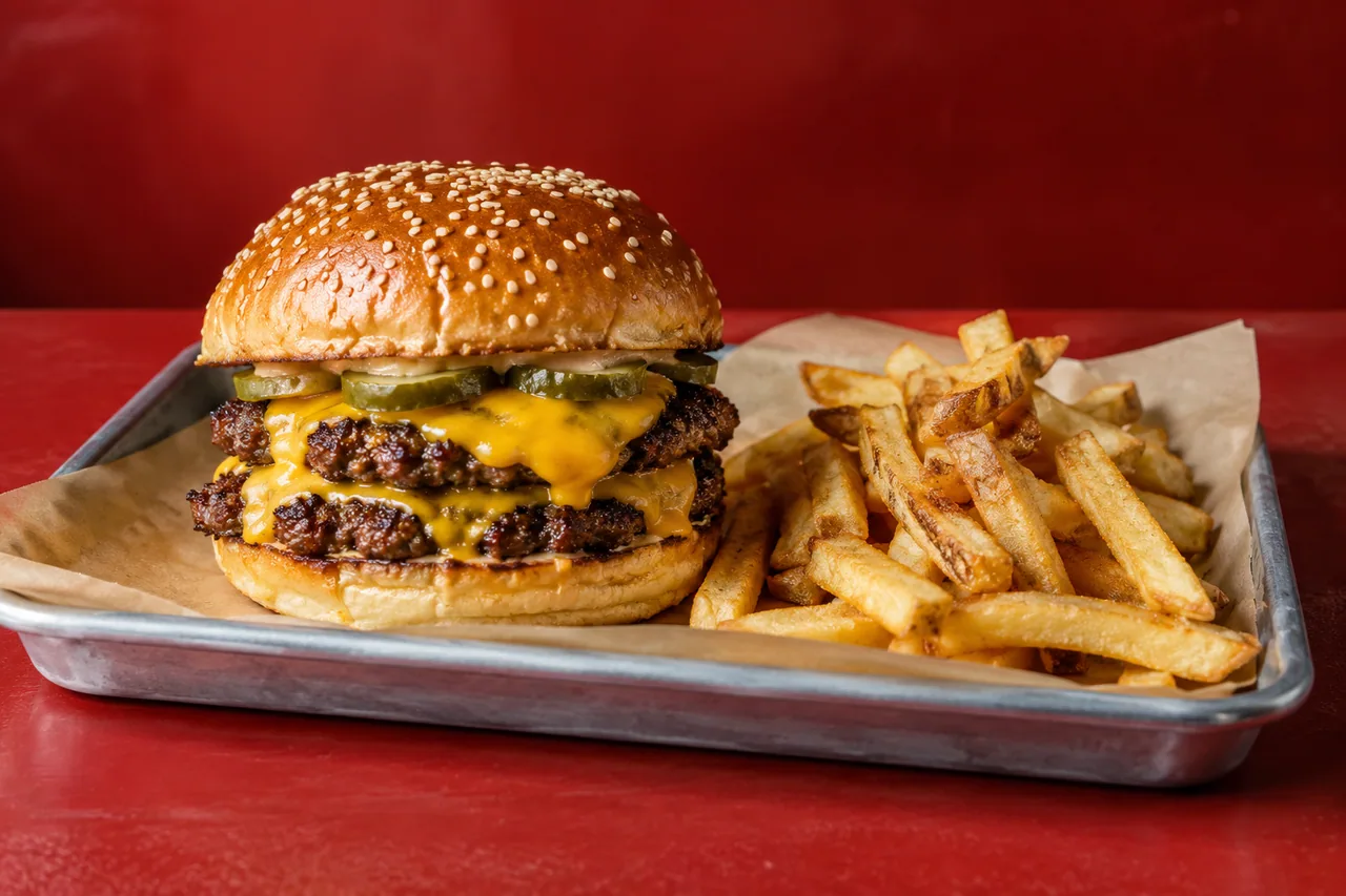 Hamburguesa doble ficticia con queso, pepinillos y patatas